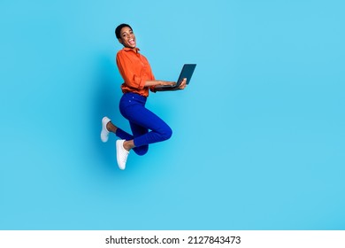 Photo of crazy programmer carefree lady jump hold pc do project remote wear brown shirt isolated blue color background