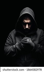Photo of a creepy vile criminal in hoodie standing in dark.