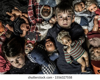 Photo of creepy young children on the floor surrounded by old dolls for Halloween theme.