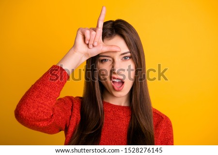 Photo of cruel rude bad school youngser showing you lose sign grimacing arrogant facial expression isolated over yellow vibrant color background