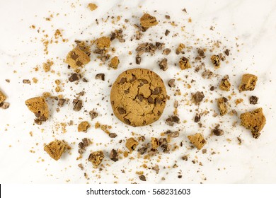 A Photo Of A Crunchy Chocolate Chips Cookie With Crumbs Around It, Shot From Above On A White Marble Background, With Copyspace