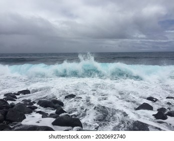 Photo of crushing bright turquoise waves on a black rocks beach in Hawaii big island. Virtual background photo. Digital cover for book, instagram post, linkedin profile, facebook post. Clouds theme