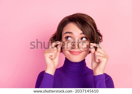Photo of curious brunette young lady hold spectacles look empty space wear violet turtleneck isolated on pink background