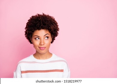 Photo of curious sly black skinned girl glancing at empty space wearing striped white sweater planning her life isolated over pink pastel color background