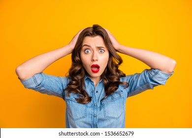 Photo of curly wavy brunette horrified feared girl in jeans denim holding her head after seeing her exams failed with face expressing disappointment isolated over yellow vibrant color background