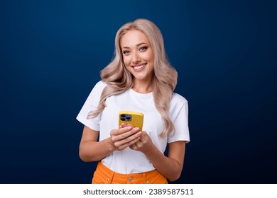 Photo of cute adorable girl dressed white trendy clothes hold phone samsung iphone isolated on dark blue color background