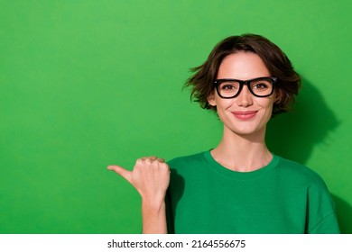 Photo Of Cute Adorable Woman Wear Casual T-shirt Eyeglasses Pointing Thumb Empty Space Isolated Green Color Background