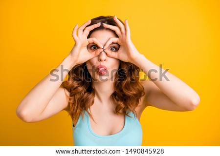 Photo of cute charming beautiful attractive pretty girlfriend wearing teal singlet fooling with her hands making glasses while isolated with yellow vibrant color background