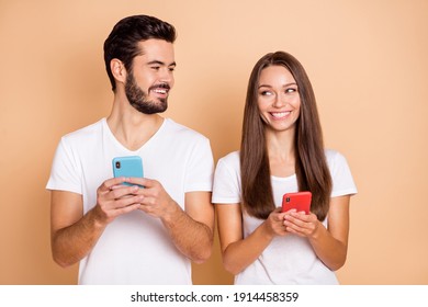 Photo of cute charming husband wife wear white t-shirts chatting modern gadgets isolated beige color background