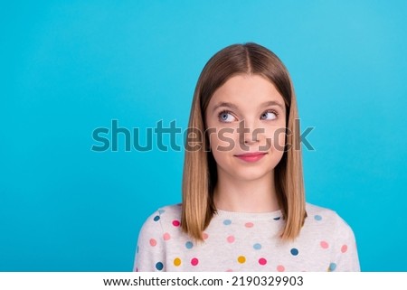 Photo of cute charming little lady dressed dotted pullover smiling looking empty space isolated blue color background
