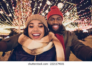 Photo of cute excited boyfriend girlfriend dressed winter season outfits recording video x-mas fair outdoors urban city street