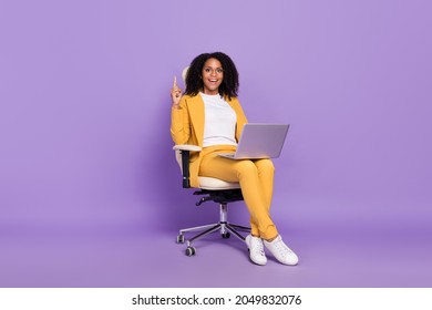 Photo of cute excited woman dressed yellow suit spectacles sitting chair chatting modern device isolated violet color background