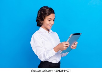 Photo Of Cute Funny School Boy Wear Formal Outfit Smiling Looking Modern Device Isolated Blue Color Background