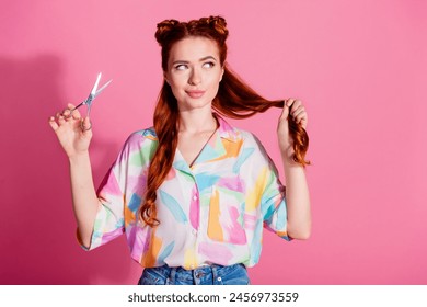 Photo of cute girl dressed colorful blouse look at red tail in arm hold scissors changing hairstyle isolated on pink color background