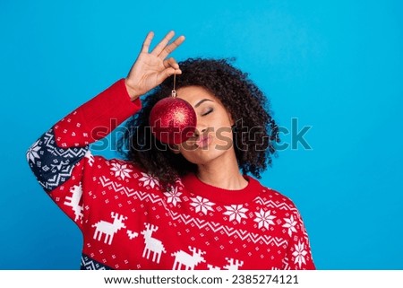 Photo of cute girl dressed stylish print sweater hand showing red ball holly jolly advent spirit isolated blue color background