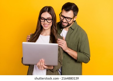 Photo of cute intelligent couple surfing in internet choose clothes buy stuff isolated on yellow color background
