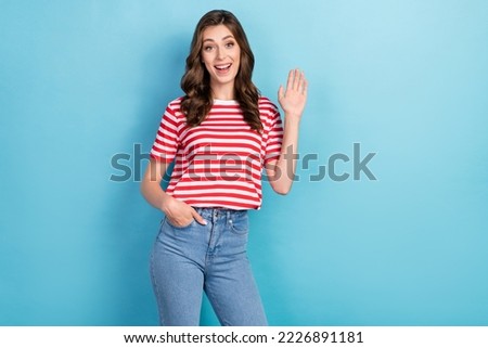 Photo of cute joyful lady wear fashionable clothes raise arm glad see meet you say hello empty space isolated on blue color background