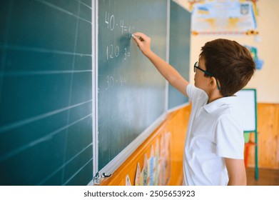 Photo of cute little schoolboy diligent write chalk solve math problem dressed stylish uniform classroom blackboard background - Powered by Shutterstock