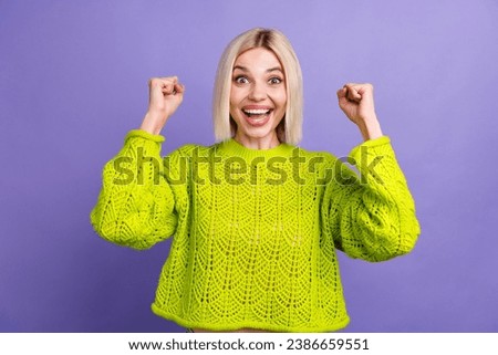 Photo of cute lucky lady wear green pullover rising fists screaming yeah isolated purple color background