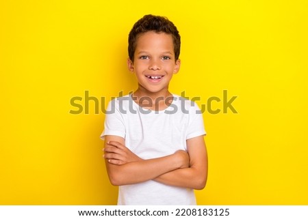 Photo of cute pretty preteen boy beaming smile wear stylish white clothes outfit arm crossed isolated on yellow color background