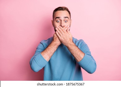 Photo of cute scared young man dressed blue sweater arms cover mouth looking down empty space isolated pink color background