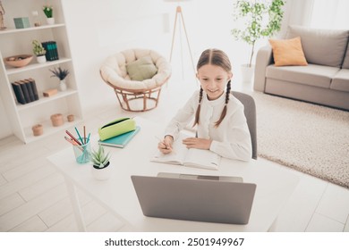 Photo of cute small girl study online laptop desk write notepad modern apartment indoors - Powered by Shutterstock