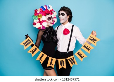 Photo Of Cute Spooky Couple Man Lady Cuddle Hold Flagged Ribbon Demonstrate Festival Opening Wear Black Short Mini Dress Death Costume Roses Headband Suspender Isolated Blue Color Background