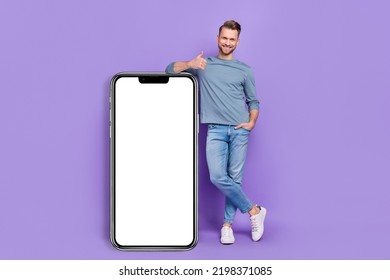 Photo of cute sweet guy dressed grey shirt showing thumb up modern gadget empty space isolated purple color background