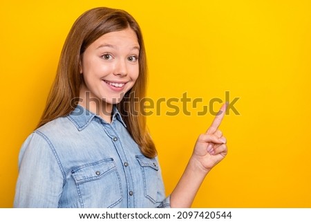 Photo of cute teenager blond girl point promo wear jeans shirt isolated on yellow color background
