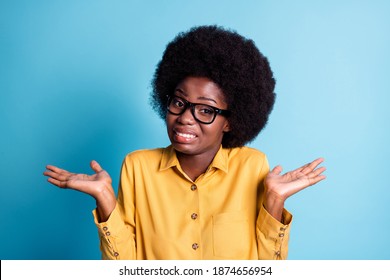 Photo of dark skin extensive hairstyle woman unsure choosing indian comedies want avoid awkward choice pretend clueless wear eyeglasses yellow shirt isolated blue color background