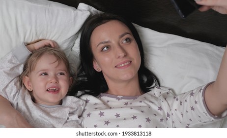 Photo Of Daughter's Mother And Child, Authenticity. New Generation, Always In Touch. Happy Family Mom, Baby Take A Picture On Smartphone, Selfie Or Video Call To Dad Or Relatives In Bed. Modern Gadget