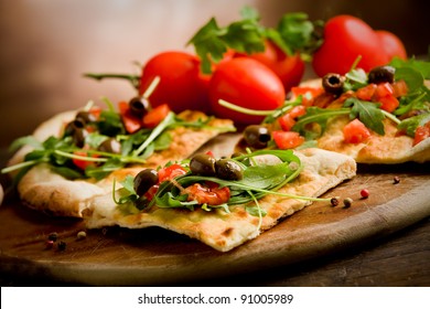 Foto von leckeren vegetarischen Pizzen mit Arugula auf Holztisch