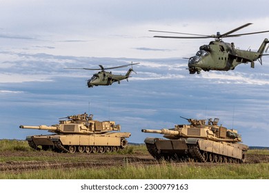The photo depicts a powerful combination of American M1 Abrams tanks Mi-24 helicopters, which have been deployed to support the Ukrainian military in their ongoing conflict, providing advanced fir