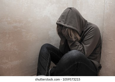 Photo Of Desperate Young Drug Addict Wearing Hood And Sitting Alone In Corner.
