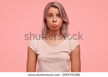 Photo of discontent female with gloomy expression, has dyed short hair, pouts lips, complains about divorce with husband to close friend, has tragic event in life, wears casual light pink t shirt