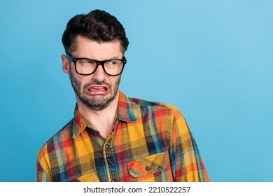 Photo of disgusted brunet guy look empty space wear spectacles plaid shirt isolated on blue color background