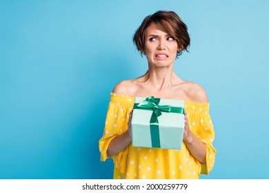 Photo Of Disgusted Young Woman Hold Dislike Gift Look Empty Space Bad Mood Isolated On Blue Color Background