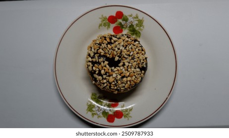 Photo of donuts with chocolate and peanut toppings on a small white plate with floral motif - Powered by Shutterstock