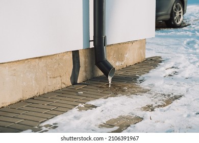 Photo Of A Downpipe In Winter With Frozen Water And A Car In The Background