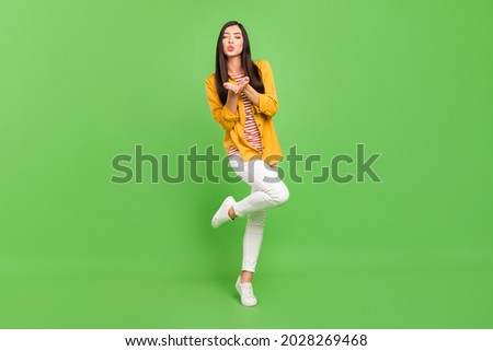 Photo of dreamy adorable young woman dressed casual clothes sending you air kiss walking isolated green color background