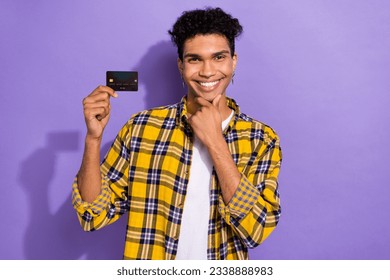 Photo of dreamy clever guy dressed checkered yellow shirt arm chin holding credit card isolated purple color background - Shutterstock ID 2338888983