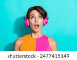 Photo of dreamy excited lady dressed colorful top listening songs earphones looking up empty space isolated turquoise color background