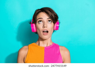 Photo of dreamy excited lady dressed colorful top listening songs earphones looking up empty space isolated turquoise color background - Powered by Shutterstock