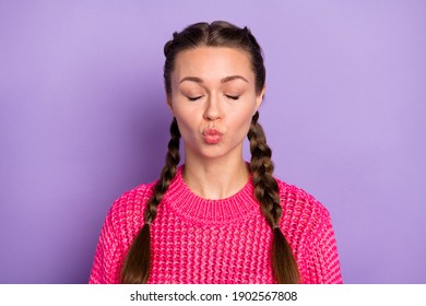 Photo of dreamy flirty young woman send air kiss closed eyes wear pink sweater isolated on violet color background