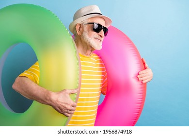 Photo of dreamy happy cheerful old man look empty space hold swim rings smile isolated on blue color background - Powered by Shutterstock