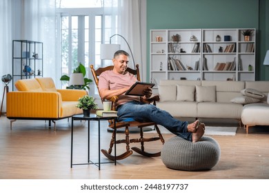 Photo of dreamy Indian matured man sitting on rocking chair looking at photo frame inside posh home - Powered by Shutterstock