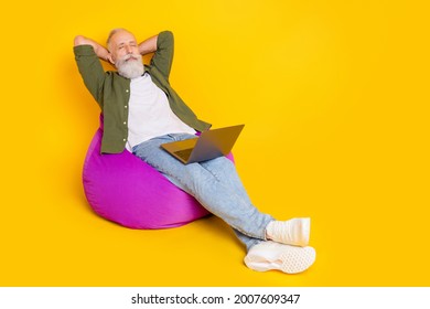 Photo Of Dreamy Old Man Sit Beanbag Sleep Hold Laptop Wear Green Shirt Isolated Yellow Color Background