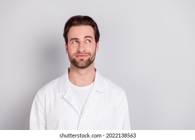 Photo of dreamy positive young doc man dressed white coat smiling looking empty space isolated grey color background