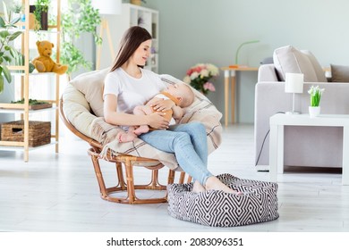 Photo Of Dreamy Pretty Lady Wear White T-shirt Smiling Sitting Chair Holding Arms Hands Rocking Sleep Baby Inside Indoors House Room