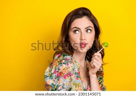 Photo of dreamy shiny lady wear retro flower print blouse licking lollipop looking empty space isolated yellow color background